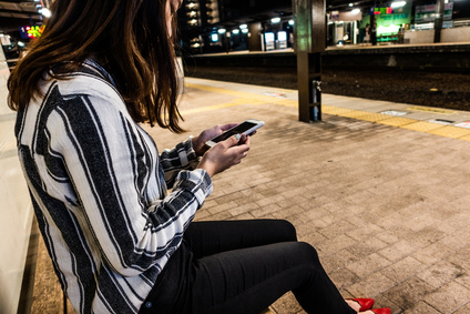 駅のホームでスマホを操作する女性