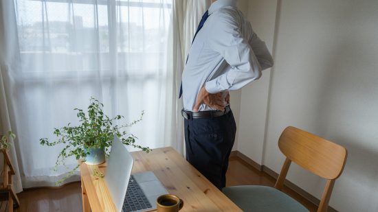 デスクワークで腰痛のビジネスマン。腰のストレッチ。