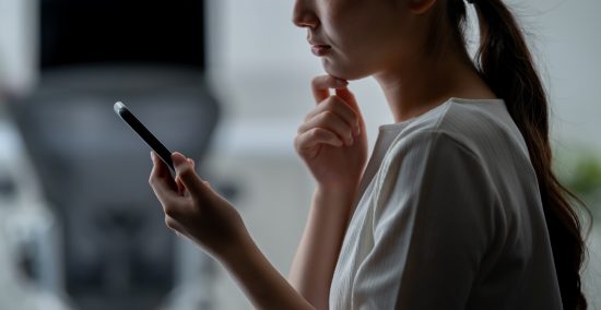 スマートフォンを見て考える女性