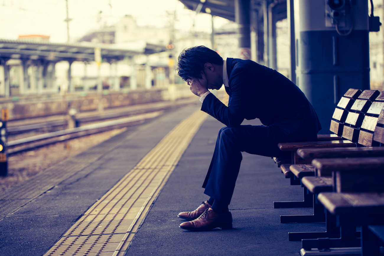 駅のホームで落ち込む男性