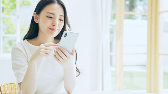 笑顔でスマホを見る女性