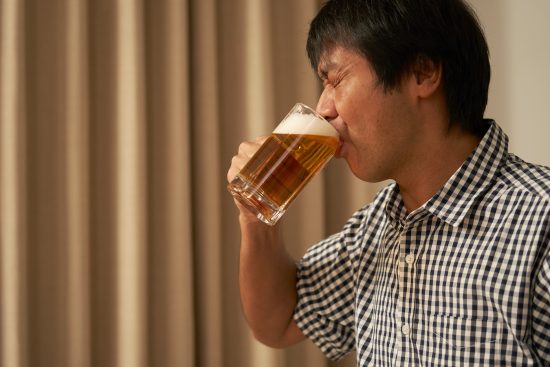 夜のリビングでビールで飲む中年男性