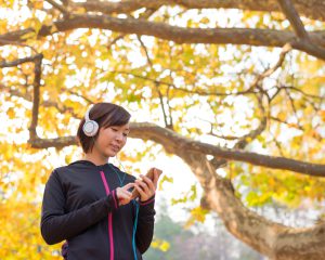 スマートフォンで音楽を聞きながらウォーキングする女性