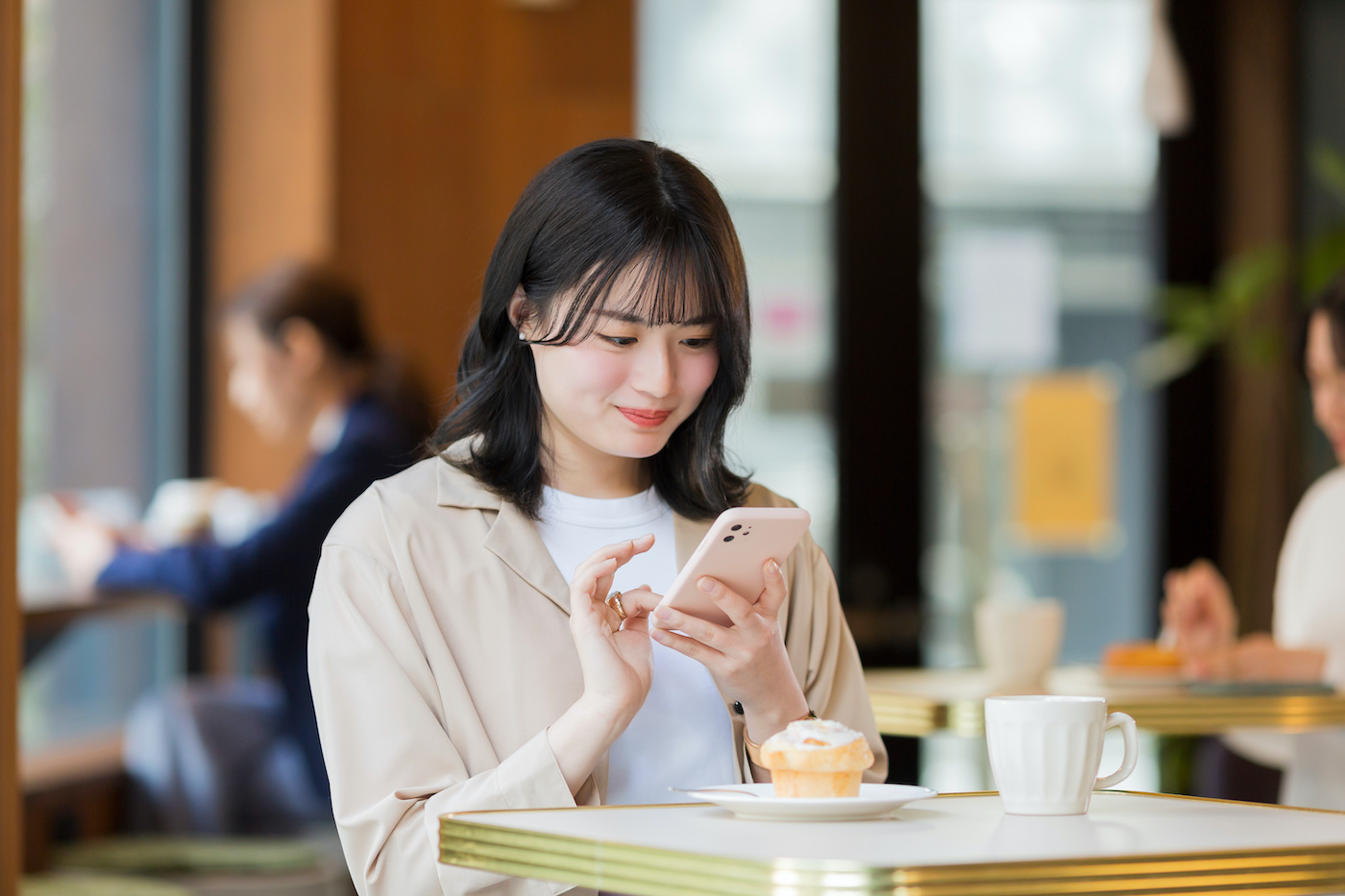 カフェでスマホを見る若い女性