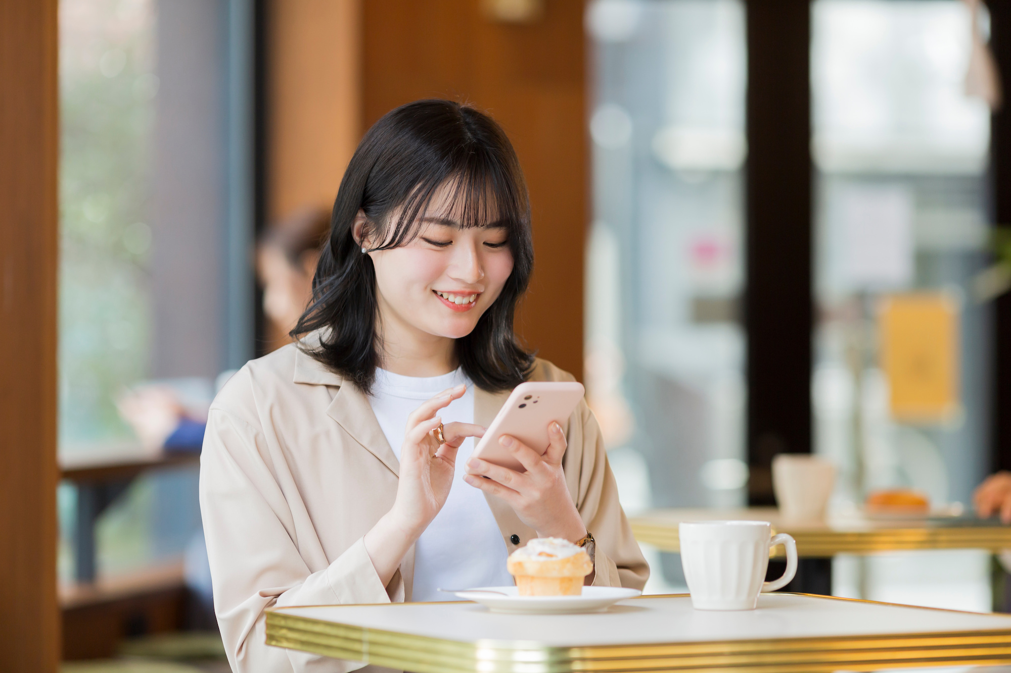 カフェでスマホを見る若い女性