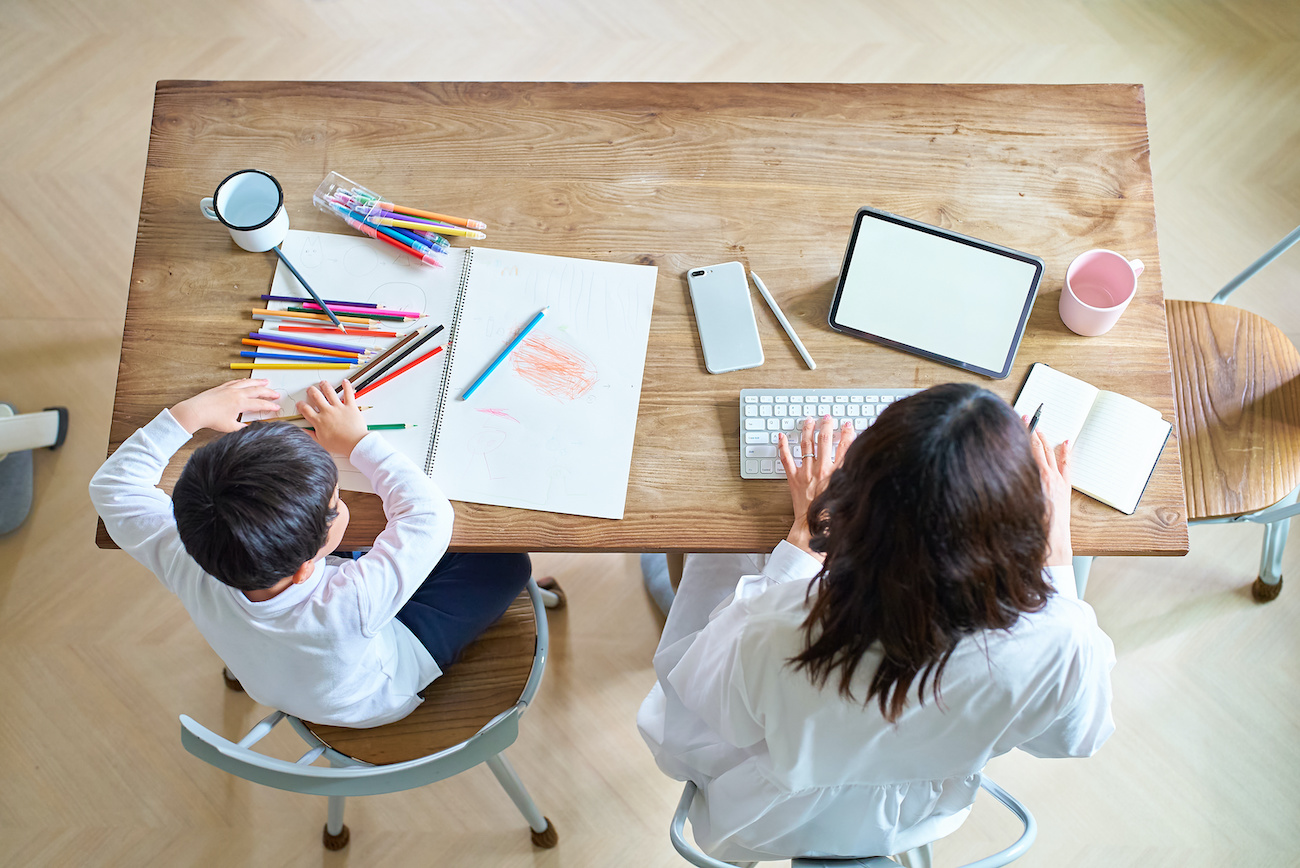 部屋で仕事をする母親と、お絵描きをする子供