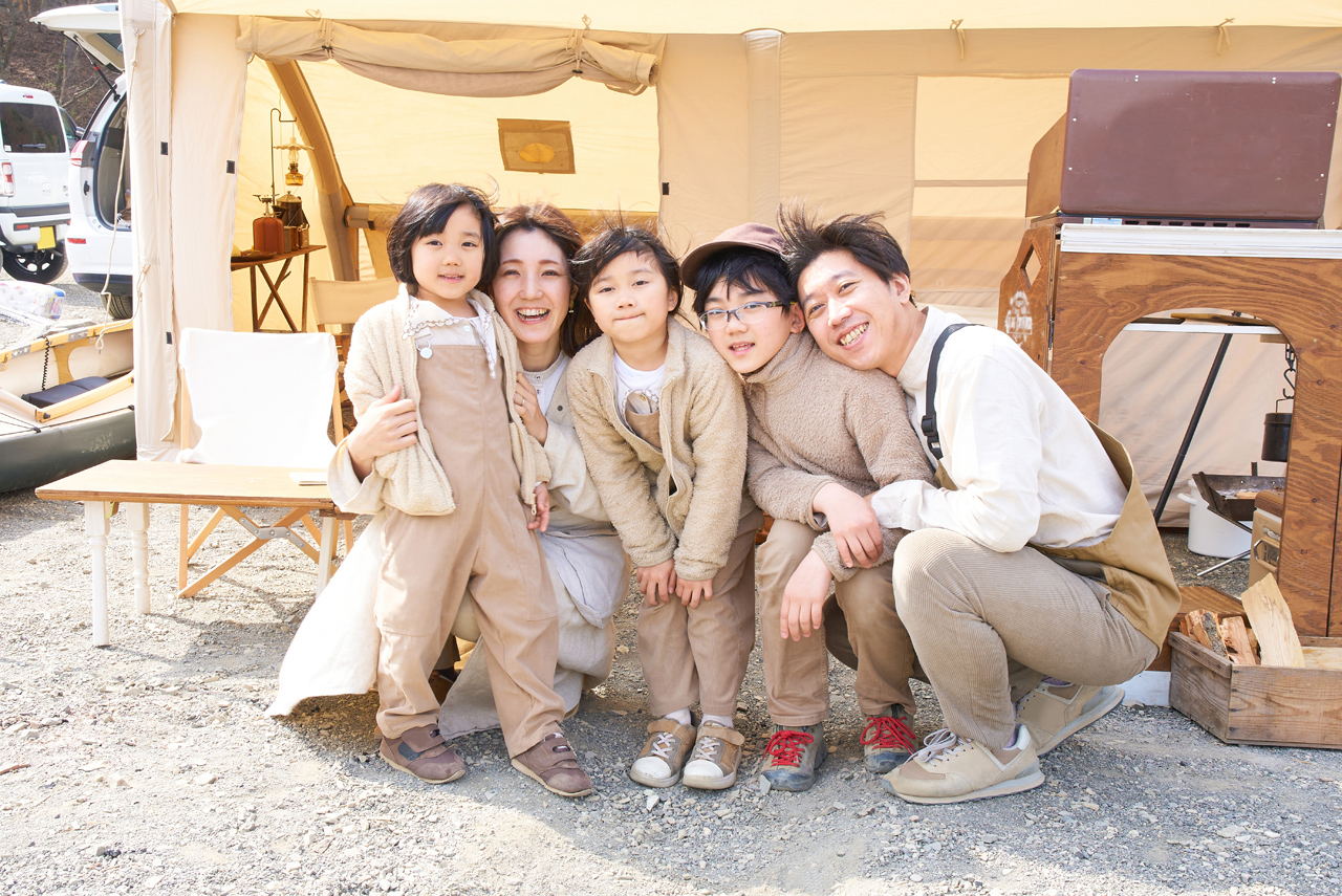 A family lined up in front of a tent at a campsite