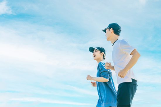 青空の下でジョギングをする日本人の男女