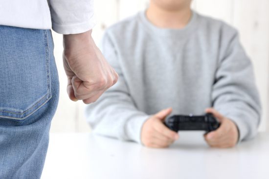 ゲームに夢中な子供に怒りを感じる母親の手元